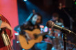 © carbonyte - Acoustic trio band performing on a stage in a nightclub, with the microphone in focus waiting for its singer