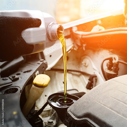 Fotomural Fresh oil being poured during an oil change to car engine in rays of the sun, cl
