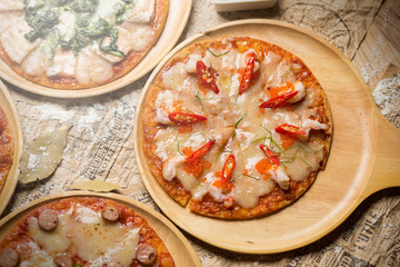 Fresh delicious Italian pizza with mushrooms on thin crust, on a wooden serving plate