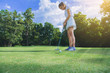 © Panumas - pretty woman golfer putting a golf ball into hole.