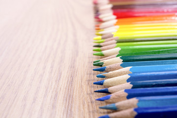 Many multicolored pencils on a wooden background. Different colored pencils with space for text. Copyspace. Back to school.