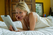 © PhotoAlto - Mature woman relaxing with digital tablet on bed