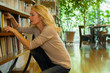 © PhotoAlto - Mature woman looking at books on shelf at home