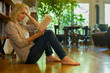 © PhotoAlto - Mature woman sitting on floor reading book at home