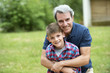 © PhotoAlto - Grandfather embracing grandson outdoors, portrait