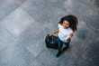 © bnenin - Top view portrait of young woman with afro hairstyle walking on the street with luggage.