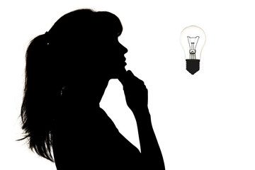 silhouette of thoughtful girl looking at the incandescent lamp upwards, thought bulb, concept of idea on white isolated background