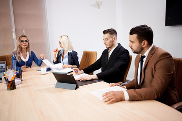 Team of business people at meeting in the conference room. They are discussing new projects. Two successful business women and two businessmen at the desk.