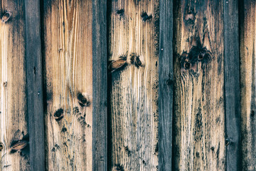 Vertical striped background from old faded boards. Wooden texture from brown vintage planks and laths with dark knots.