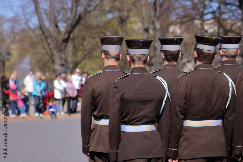 Obraz na płótnie Łotwa, Ryga, oficjalna ceremonia z udziałem łotewskiej armii, święto narodowe Łotwy, grupa żołnierzy, tyłem, na drugim planie niewyraźna grupa ludzi uczestnicząca w święcie, park w salonie