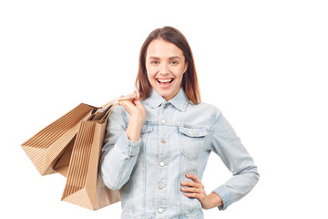 Portrait of young woman in denim jacket holding shopping bags on white background