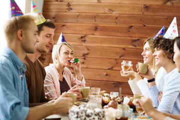 Wall Mural - Restful friends having fun by birthday table and enjoying party