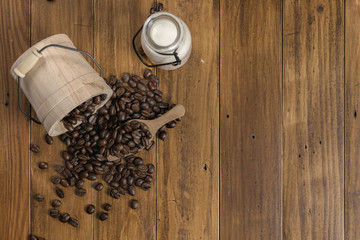 Wall Mural - Coffee bean grain ,bottle of milk and sack fabrice board on brown wood table background , include copyspace for add text or graphic in advertise or marketing content