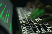 Cyber Crime Concept: Hands Of A Person Hacking On Laptop In The Darkness