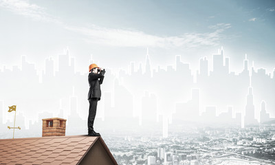 Engineer man standing on roof and looking in binoculars. Mixed m