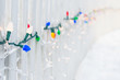 Colorful Christmas lights along a white fence