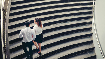 Businessman and Business woman go up the stairs Success concept