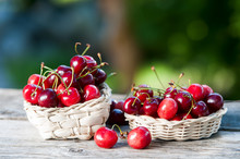 Basket With A Cherry On A Wooden Table On A Background Of A Green Garden.