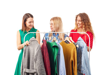 Wall Mural - Three young woman browsing through clothes on rack