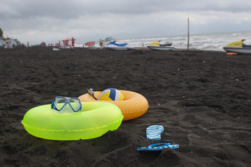 Ball, swimming glasses, sandal, Water scooter and two Floating Ring on beach. In the summer vacation