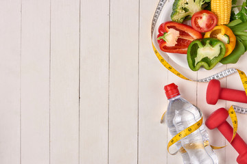 Wall Mural - Bell pepper with measuring tape, dumbbells and bottle of water, isolated on white