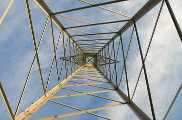 Metal power post view from below against a sky with clouds