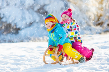 Wall Mural - Kids play in snow. Winter sleigh ride for children