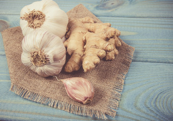 Garlic bulbs with ginger on blue wooden table. Concept of natural medicine.