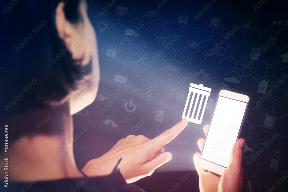 Image of a girl with a smartphone in hands. She presses on the trash can icon. The concept of deleting files, contacts, putting in order, cleaning service etc.