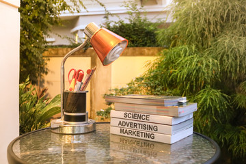 Several textbooks on glass table with table lamp