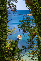 Wall Mural - Coastal landscape - the boat in bay with view through trees, near city of Sozopol on the Black Sea coast in Bulgaria