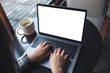 © Farknot Architect - Mockup image of business woman using and typing on laptop with blank white screen and coffee cup on wooden table in cafe