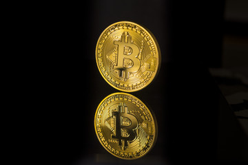 Wall Mural - Single bitcoin coin or icon standing in sharp focus on a reflective surface with black background