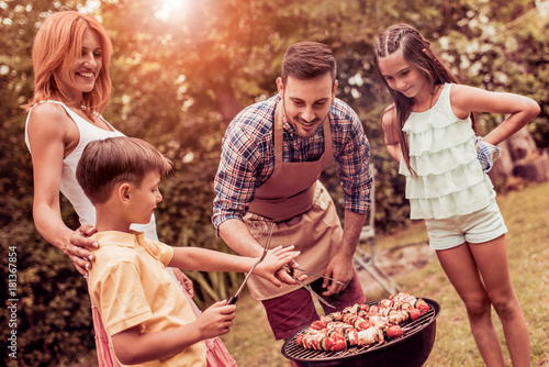 Plakat Szczęśliwa rodzina ma grilla w ich ogródzie w lecie