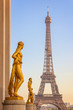 Golden bronze statues on Trocadero square, Eiffel tower in the background, Paris France