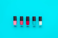 Cosmetics On Colorful Background. Nail Polish Assorted Colors On Blue Background Top View Copyspace