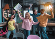 © Yakobchuk Olena - Stunning victory. Delighted young colleagues are rising their hands with documents up while celebrating finished of their successful project in office. They are screaming while feeling extremely happy