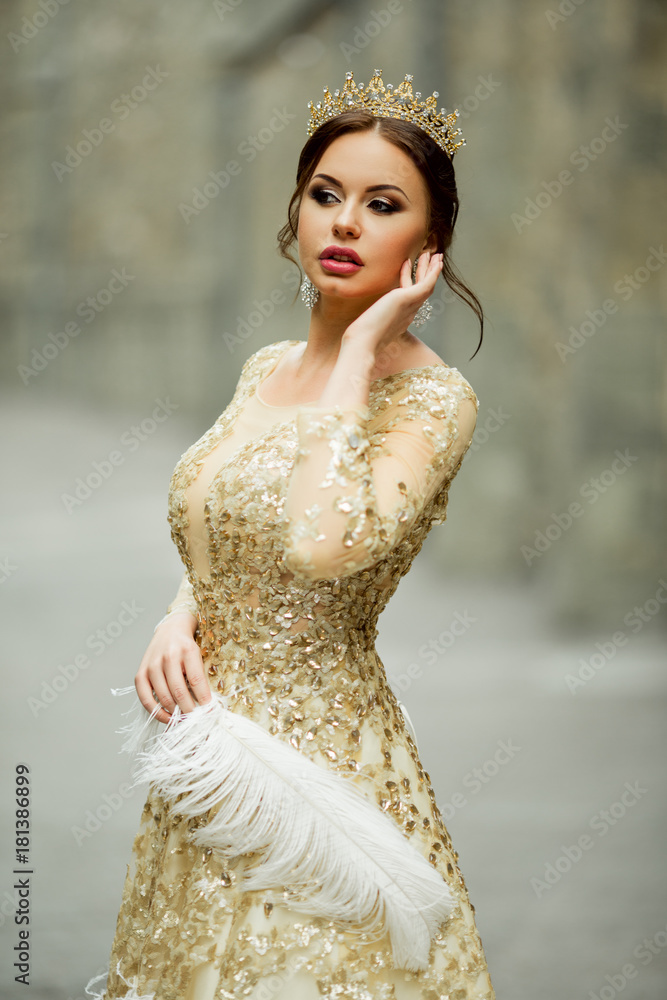 Beautiful woman with fashion makeup is wearing princess luxury dress and  crown holding white feather Stock Photo | Adobe Stock