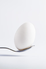 white egg on a spoon on a white background