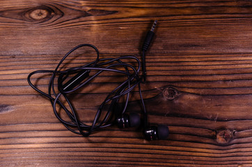 Black earphones on wooden table. Top view