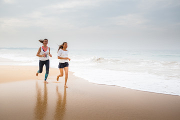 Wall Mural - two women is jogging the seashore on an overcast day