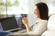 © Antonioguillem - Woman using a phone and a laptop at home