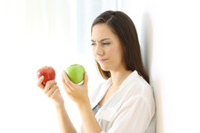 Woman Deciding Between Red And Green Apples