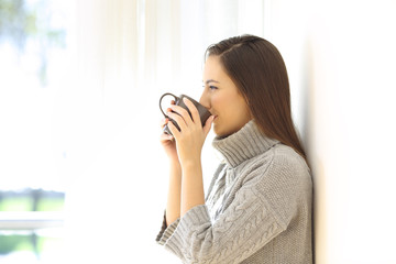 Wall Mural - Woman drinking coffee looking through a window