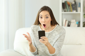 Poster - Surprised woman holding a phone looking at you