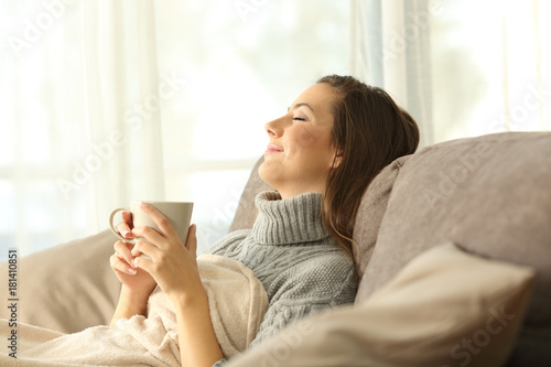 Plakat Kobieta relaksuje w domu trzyma kawowego kubek