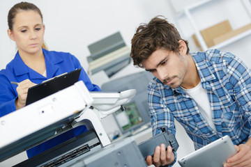 Wall Mural - young male technician using a tablet for repairing photocopier