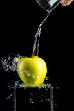 Fototapeta  - green apple is standing on  glass stand with water on black background