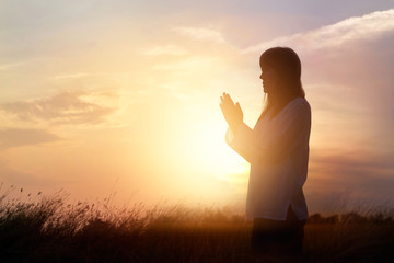 Canvas Print - Woman praying and practicing yoga on nature sunset background, hope concept