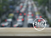 24 Hours Service Icon On Wooden Table Over Blur Of Rush Hour With Cars And Road, Full Time Service Concept